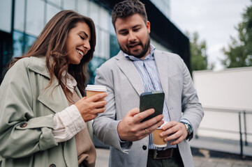Business people having coffee break using smartphone outdoors