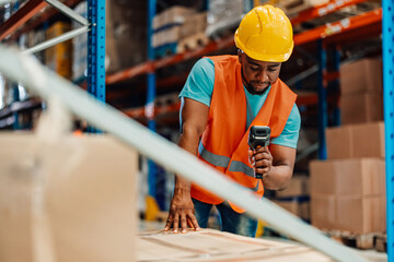 Focused warehouse worker scanning package with barcode scanner