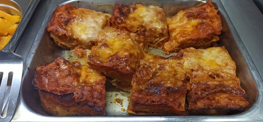 Homemade lasagna served in a metal tray at a family gathering event during evening hours