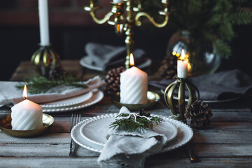 Rustic Scandinavian style zero waste eco-friendly dinner table decor for Christmas or new year family celebration. Wooden table, natural elements like pine cones, fir tree branches, candles