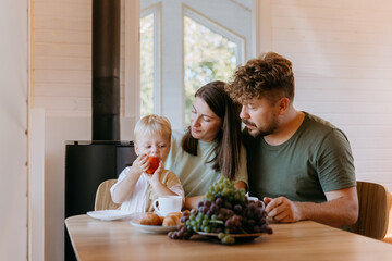 Family enjoying breakfast together with child, savoring fresh fruit and bonding over simple moments