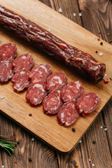 Smoked salami sticks on a wooden board with herbs, perfect for charcuterie boards and gourmet snacks