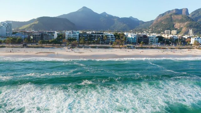 Aerial view of the waves breaking at Praia da Barra beach with mountains in the background.