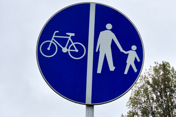 A road sign indicating separate paths for cyclists and pedestrians, promoting safety in urban areas. Ideal for topics on transportation, safety, and urban planning.