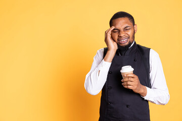 Restaurant employee dealing with a painful headache while he serves clients, carrying a cruet set for excellent customer satisfaction. Unwell waiter working in pain with migraine.