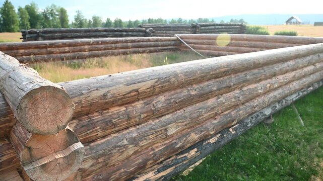 Panoramic view of constructing a wooden log cabin using traditional building techniques in a sunny rural setting