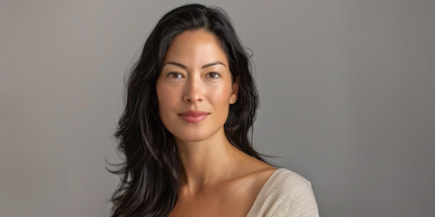 Naklejka premium Portrait of a Confident Woman with Long Dark Hair Against a Neutral Background