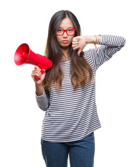 Young asian woman holding megaphone over isolated background with angry face, negative sign showing dislike with thumbs down, rejection concept