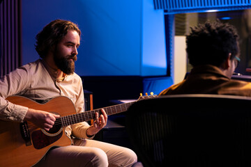 Artist recording his electro acoustic guitar tunes with producer in studio, doing mix and master to...
