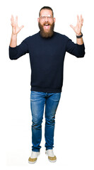 Naklejka premium Young blond man wearing glasses and turtleneck sweater celebrating crazy and amazed for success with arms raised and open eyes screaming excited. Winner concept