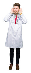 Fototapeta premium Young handsome doctor man wearing medical coat Trying to hear both hands on ear gesture, curious for gossip. Hearing problem, deaf