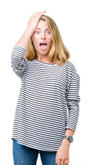 Beautiful young woman wearing stripes sweater over isolated background surprised with hand on head for mistake, remember error. Forgot, bad memory concept.