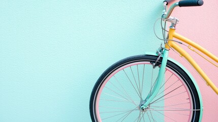 Fototapeta premium A vibrant bicycle leans against a pastel wall, showcasing a mix of teal and pink tones, embodying a playful and artistic vibe.