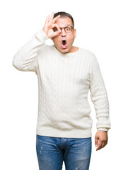 Middle age arab man wearing glasses over isolated background doing ok gesture shocked with surprised face, eye looking through fingers. Unbelieving expression.