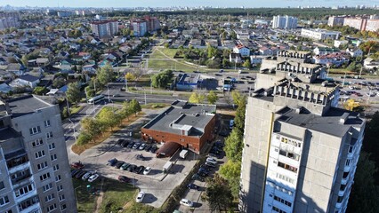 Obraz premium Minsk, Belarus - 27.10.2024: Dense building of a modern large Belarusian city. Neighborhood of one-storey huts, cottages and multi-storey residential buildings. View of the city of Minsk from a height