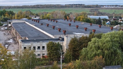 Huge two storey old brick warehouse, twentieth century logistics centre. Roof of large warehouse covered with roofing felt, with ducts, hoods.