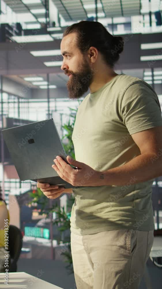 Poster vertical video cheerful admin holding laptop chatting with colleagues while working with machine lea