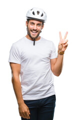 Young handsome man wearing cyclist safety helmet over isolated background smiling with happy face winking at the camera doing victory sign. Number two.