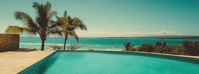Swimming pool with an ocean view and palm trees in the foreground.