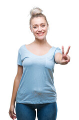 Young blonde woman over isolated background smiling with happy face winking at the camera doing victory sign. Number two.