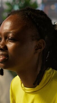 Vertical video Tired african american programmer having strained eyesight from overworking in office. Close up of woman at work removing eyeglasses to rub eyes, looking at PC screen for too long