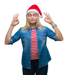 Young caucasian woman wearing christmas hat over isolated background relax and smiling with eyes closed doing meditation gesture with fingers. Yoga concept.