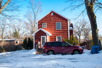 red car in front of house in the snow in winter	