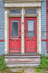 Two red doors on the front of a blue house