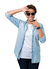 Beautiful young african american woman wearing sunglasses over isolated background smiling making frame with hands and fingers with happy face. Creativity and photography concept.