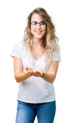 Beautiful young blonde woman wearing glasses over isolated background Smiling with hands palms together receiving or giving gesture. Hold and protection