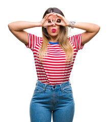 Young beautiful woman casual look over isolated background doing ok gesture like binoculars sticking tongue out, eyes looking through fingers. Crazy expression.