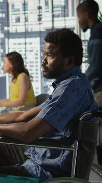 Vertical video Software technician with disability in inclusive workplace working with machine learning tech. African american IT expert with paraplegia in wheelchair transforms data into predictive