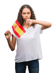 Young hispanic woman holding flag of Spain with angry face, negative sign showing dislike with thumbs down, rejection concept