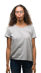 Fototapeta premium Beautiful young hispanic woman wearing glasses making fish face with lips, crazy and comical gesture. Funny expression.
