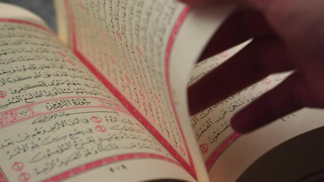 Quran (Koran) - close up of holy book of Muslims, with a man's hand turning the page.