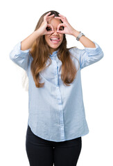 Young beautiful brunette business woman over isolated background doing ok gesture like binoculars sticking tongue out, eyes looking through fingers. Crazy expression.