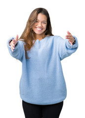 Young beautiful brunette woman wearing blue winter sweater over isolated background looking at the camera smiling with open arms for hug. Cheerful expression embracing happiness.