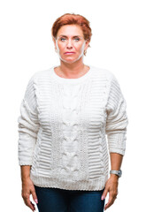 Atrractive senior caucasian redhead woman wearing winter sweater over isolated background with serious expression on face. Simple and natural looking at the camera.