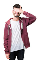 Young handsome man over isolated background smiling and laughing with hand on face covering eyes for surprise. Blind concept.