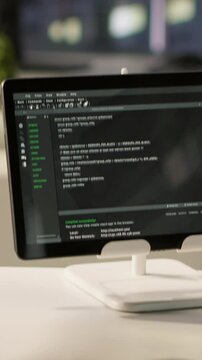 Vertical video Programming language on digital device screen in empty IT department office used for app development. Close up of tablet left open on desk in tech startup company workspace with nobody