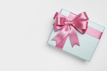 Gift box with pink bow on light grey background, top view. Space for text