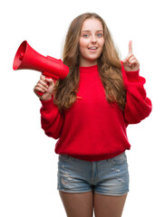 Young blonde woman holding red megaphone surprised with an idea or question pointing finger with happy face, number one