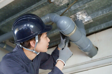 水道管の水漏れ点検工事をする女性作業員