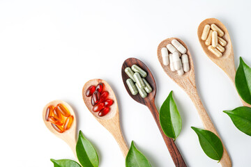 Wooden spoon with assorted herbal vegan vitamin capsules for healthy lifestyle with fresh leaves