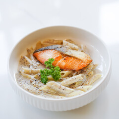 Truffle pasta with Salmon. Penna pasta with truffle sauce served with grilled salmon topping, soft focus on the salmon
