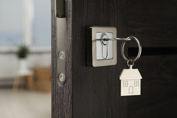 Open door with key and house shaped keychain, closeup