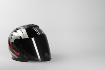 Motorcycle helmet with visor on light grey background, space for text