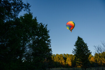 Obraz premium Colorful hot air balloon with red, green, yellow, purple, orange flying in blue sky with flame burning