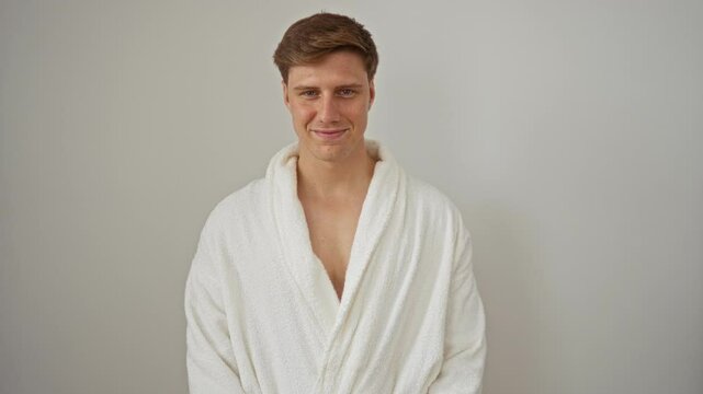 Young man wearing a white robe over an isolated white background showing a relaxed and confident expression