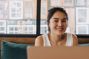 Happy Asian woman enjoy working online remotely from a co-working space cafe.